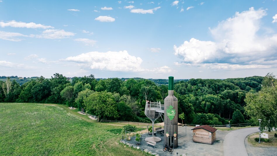 Begehbare Weinflasche mit Aussichtsplattform in Bad Loipersdorf im Thermen- & Vulkanland Steiermark, umgeben von der grünen, sanft hügeligen Landschaft.