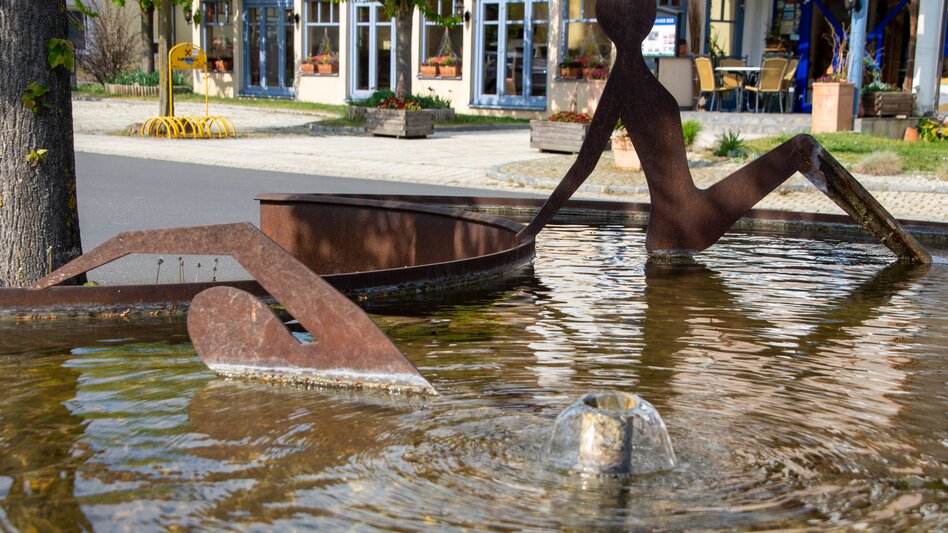 Blick auf Brunnen mit Personen aus Edelstahl