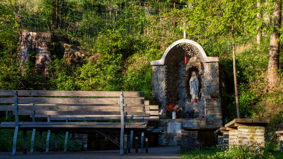 Mariengrotte mit Statue der Heiligen Maria inmitten einer bewaldeten Naturlandschaft
