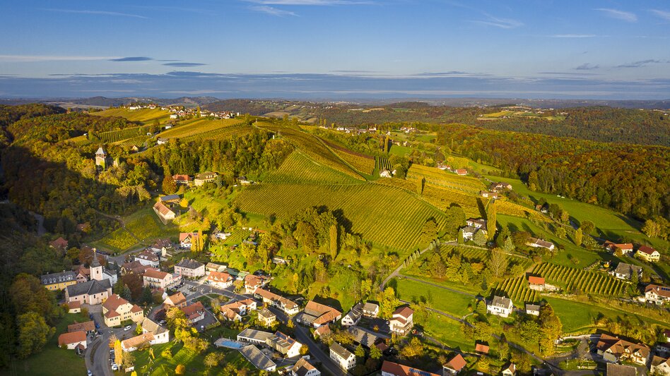 Luftaufnahme von Klöch mit herbstlichen Weingärten und sanfter Hügellandschaft im Thermen- & Vulkanland Steiermark. | © Tourismusverband Thermen- & Vulkanland | pixelmaker.at