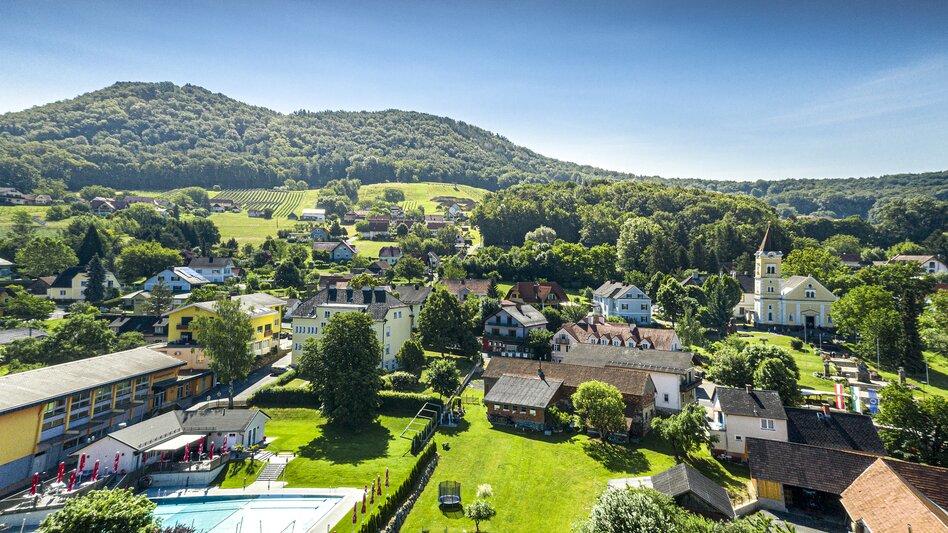 Luftaufnahme von Tieschen mit Pfarrkirche, Freibad und grünen Weinbergen