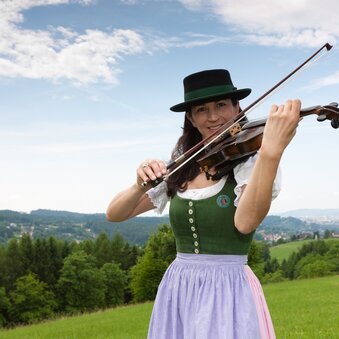 Geigenspielerin in Tracht bei Stattegg mit Panorama | © Region Graz | Harry Schiffer