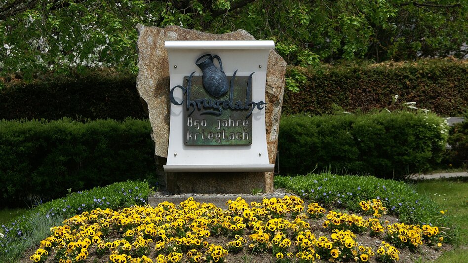 Eine Skulptur mit einem Wasserkrug, davor Blumen