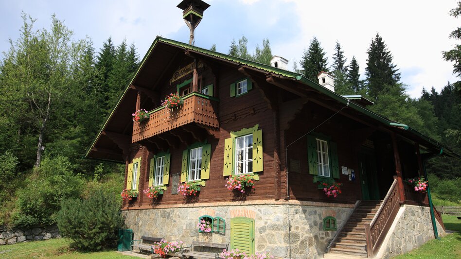 Ein altes Holzhaus im grünen, geschmückt mit Blumen.