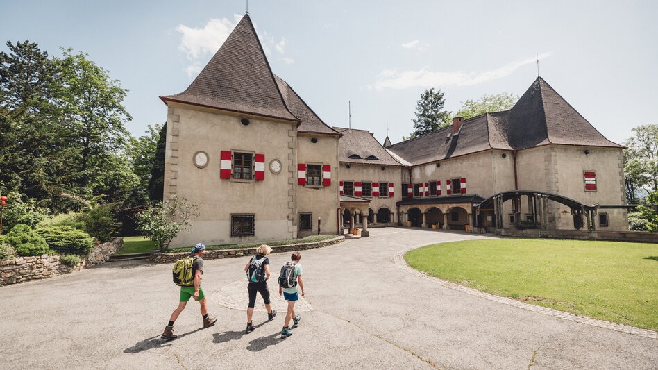 Drei Wanderer gehen an einem Sommertag auf das Schloss zu.
