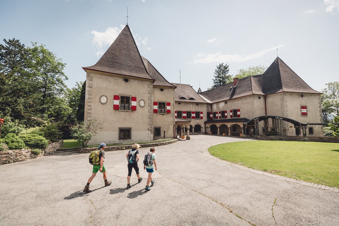 Drei Wanderer gehen an einem Sommertag auf das Schloss zu.