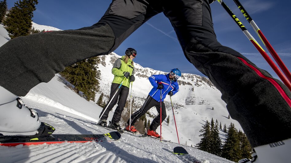 Ein Pärchen steht auf der Piste, ein Mann fotografiert das Paar